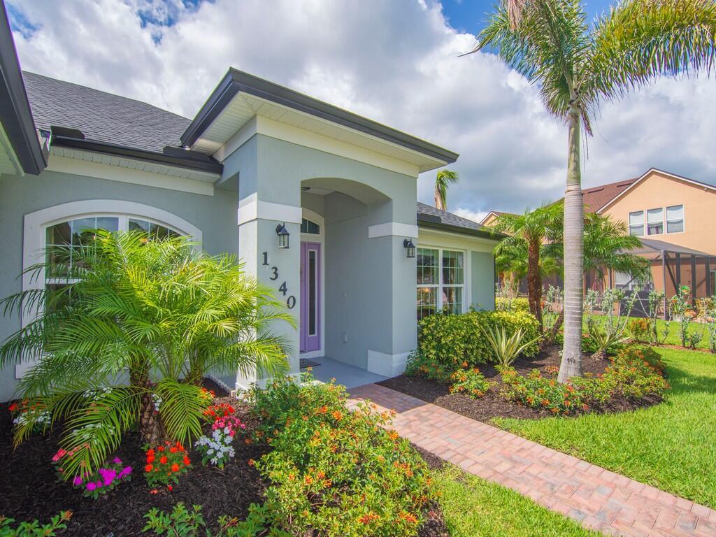 A light gray house exterior features a purple front door, palm trees, and brick walkway — 1340 Willow Oak Court, Vero Beach FL 32966, VERO BEACH, FL