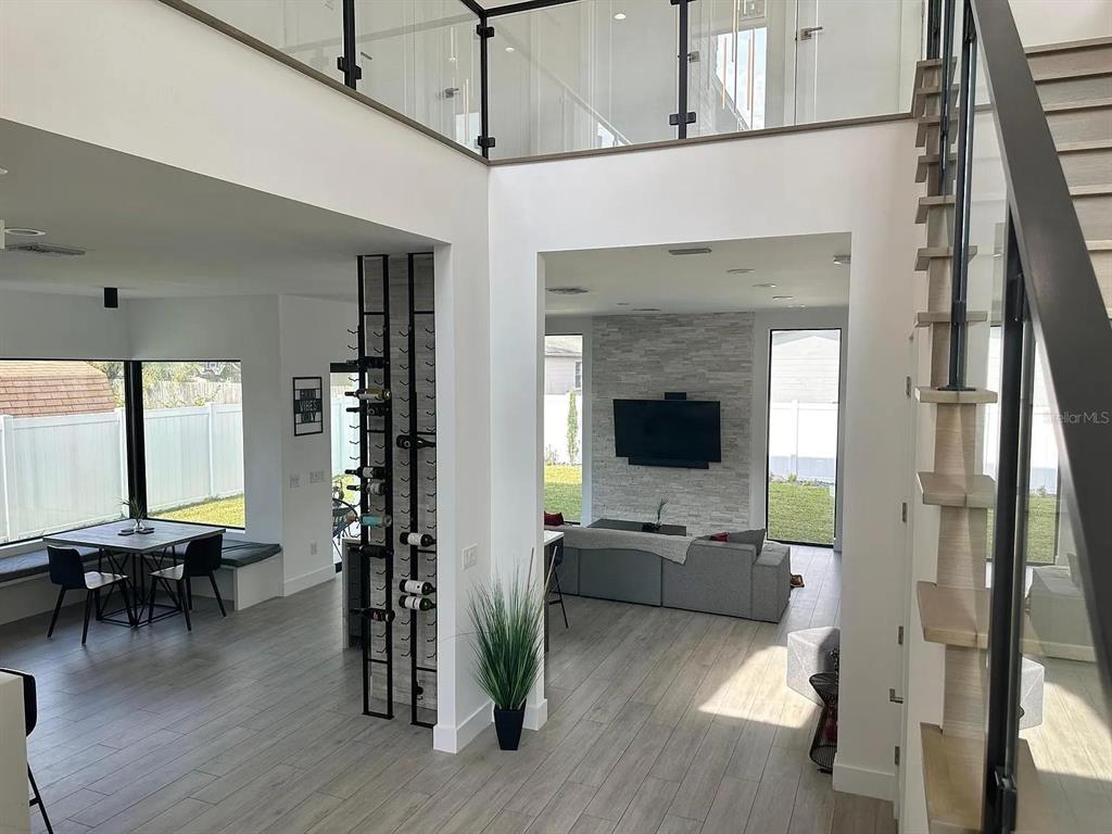 An open-concept living area features a stone fireplace, a wine rack, and a floating staircase — 4217 W ARCH STREET, TAMPA, FL
