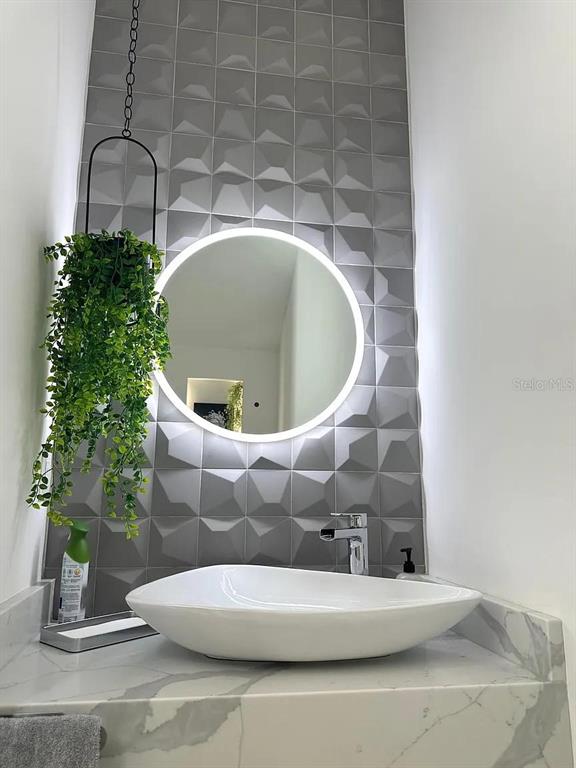 A modern bathroom features a vessel sink, a circular LED mirror, and geometric gray wall tiles — 4217 W ARCH STREET, TAMPA, FL