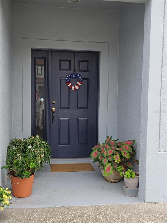 A dark blue front door with a patriotic wreath sits under a covered entryway — 2904 GRAFTON DRIVE, KISSIMMEE, FL