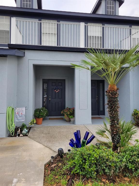The exterior of a two-story townhouse features a concrete walkway, a palm tree, and two entryways — 2904 GRAFTON DRIVE, KISSIMMEE, FL
