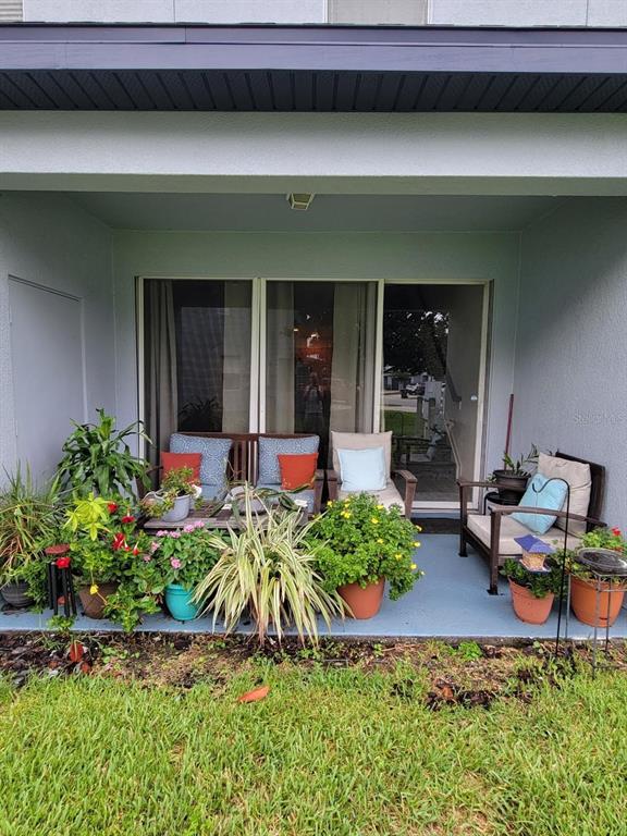 A covered patio features potted plants, outdoor seating, and a sliding glass door entrance — 2904 GRAFTON DRIVE, KISSIMMEE, FL
