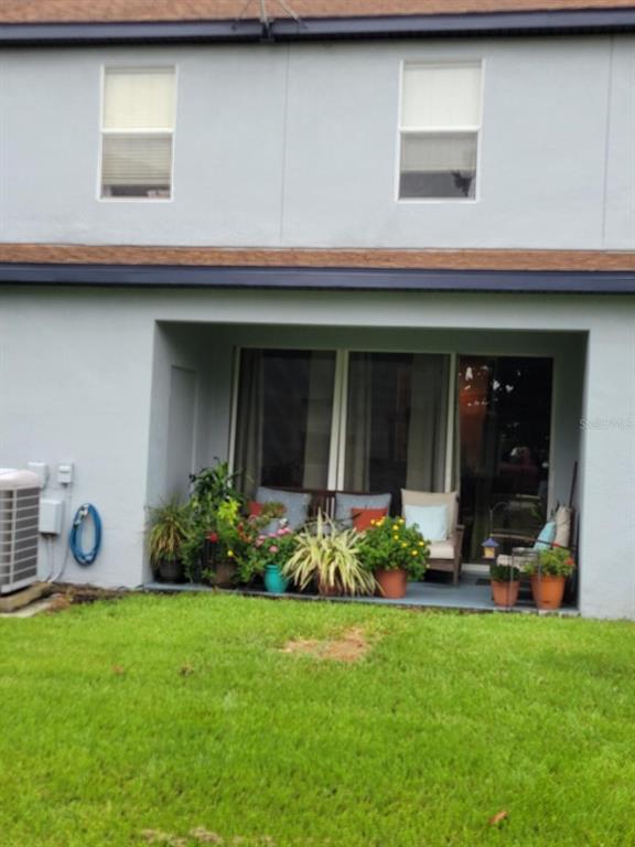 A ground-level patio with potted plants and outdoor seating sits beneath a two-story residential building — 2904 GRAFTON DRIVE, KISSIMMEE, FL