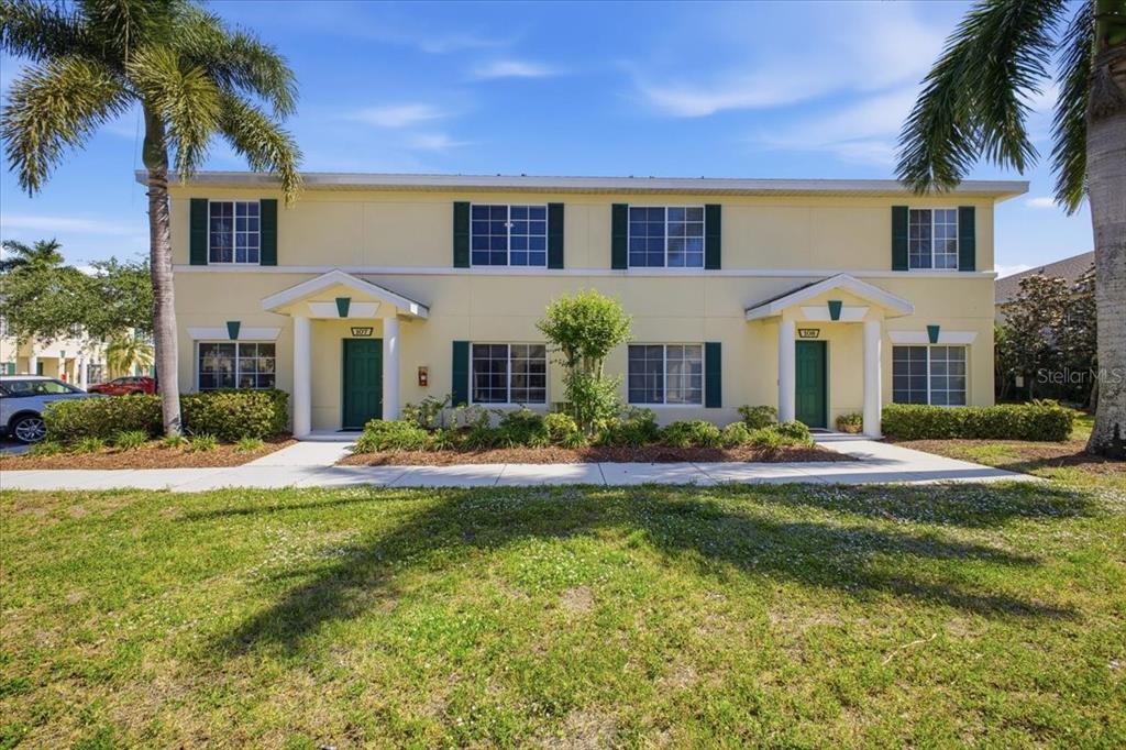 A two-story yellow townhouse with green shutters and a palm tree in the front yard — 233 CAPE HARBOUR LOOP UNIT 107, BRADENTON, FL