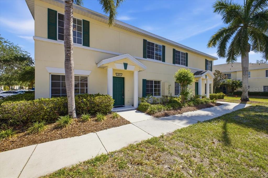 A two-story yellow apartment building with green shutters and two front entrances — 233 CAPE HARBOUR LOOP UNIT 107, BRADENTON, FL