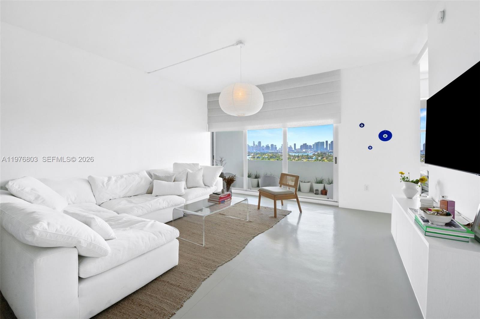 A bright living room features a white sectional sofa, glass coffee table, and city view — 3 Island Ave # G, Miami Beach FL 33139, MIAMI BEACH, FL