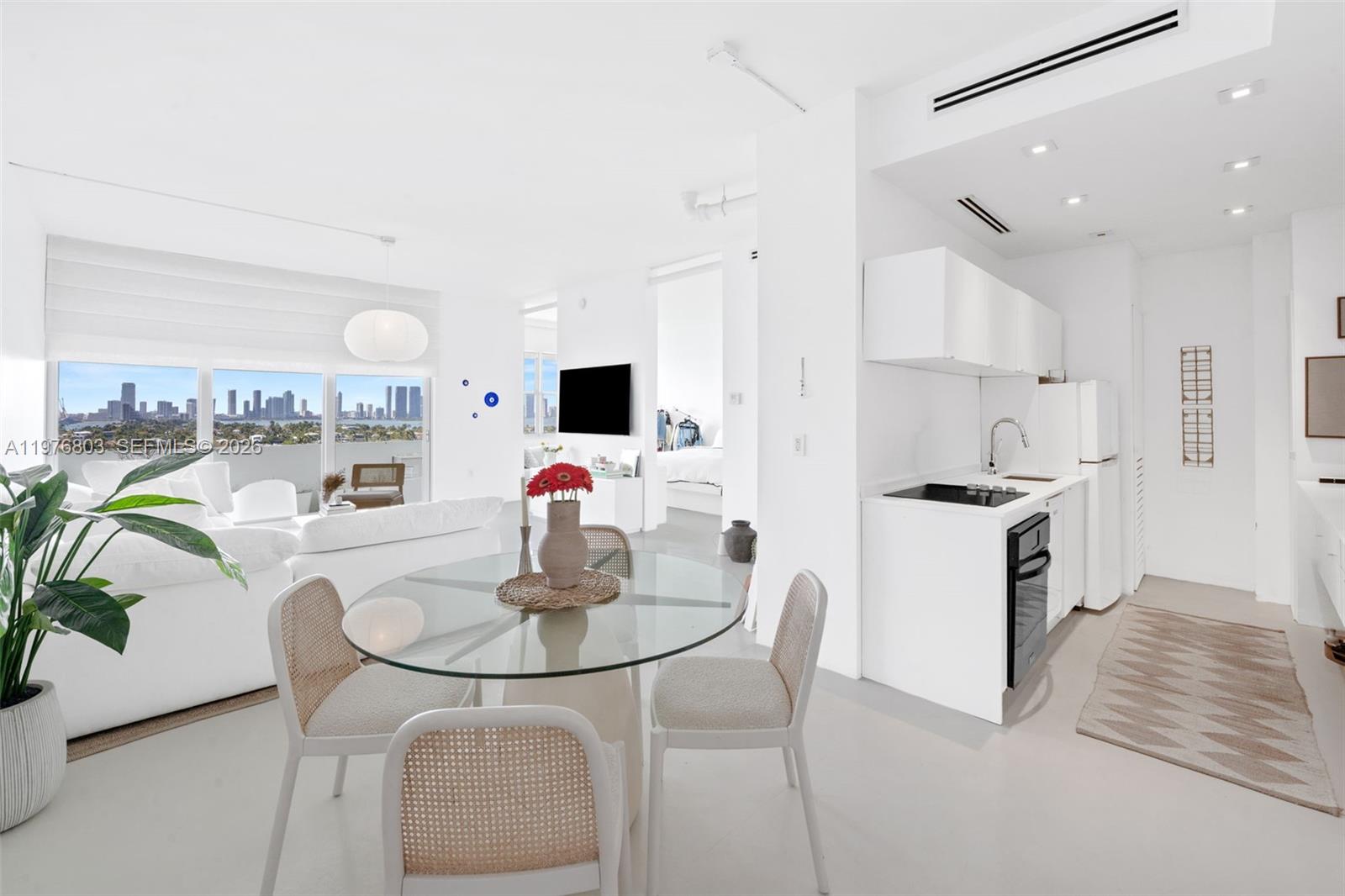 A bright, open-concept living and dining area features white decor, a glass table, and city views — 3 Island Ave # G, Miami Beach FL 33139, MIAMI BEACH, FL