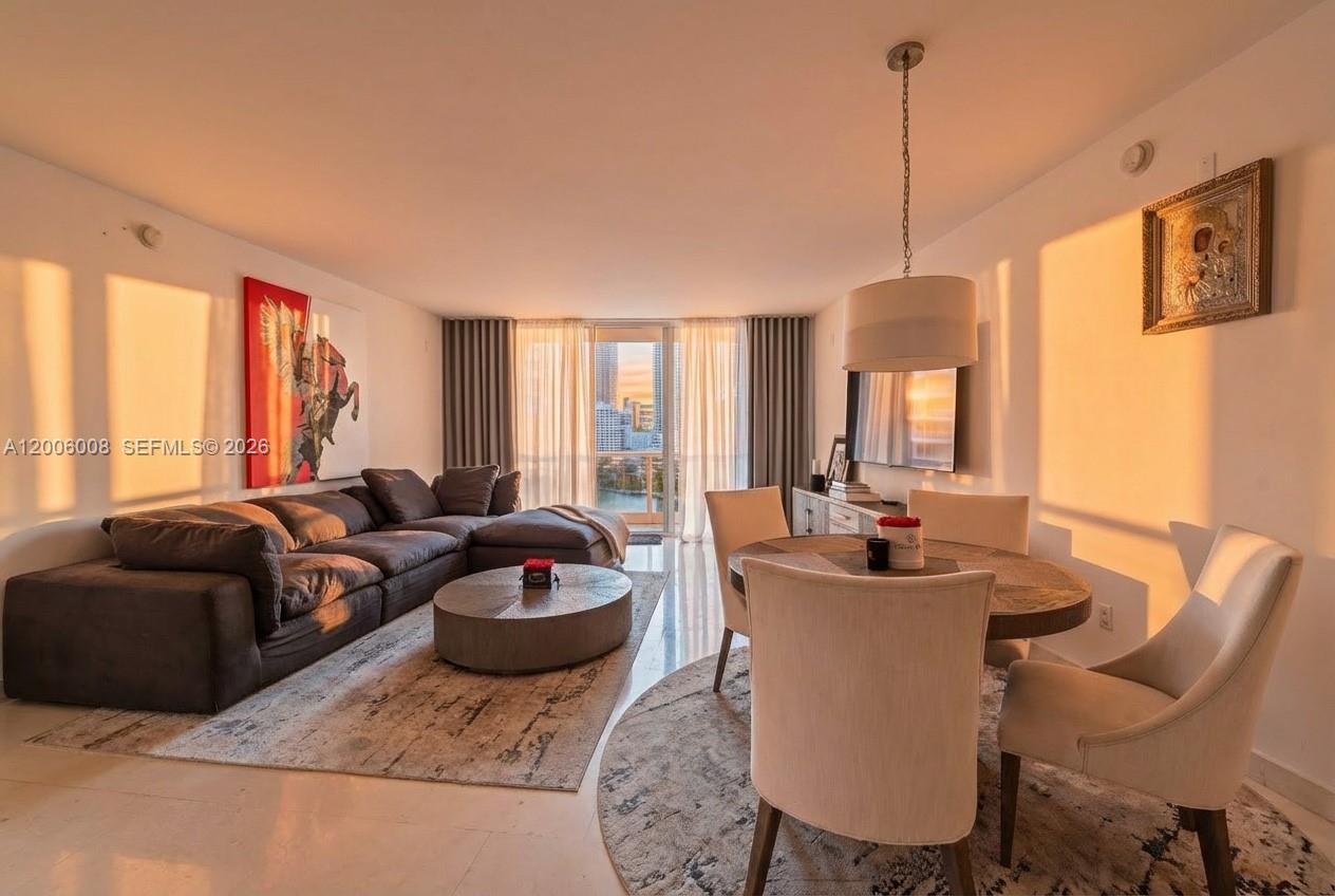 A living and dining area features a large sectional sofa, round table, and balcony view — 901 Brickell Key Blvd # 1009, Miami FL 33131, MIAMI, FL