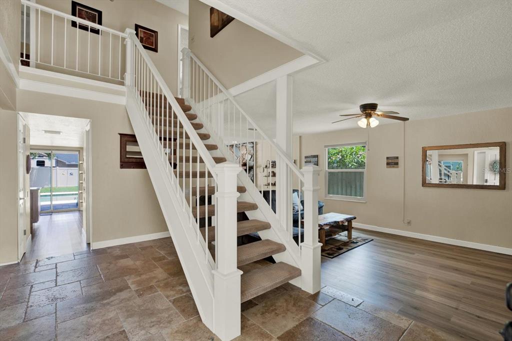 A foyer features a carpeted staircase with white railings, tile flooring, and an adjacent living area — 7363 ROSETREE PLACE E, SEMINOLE, FL