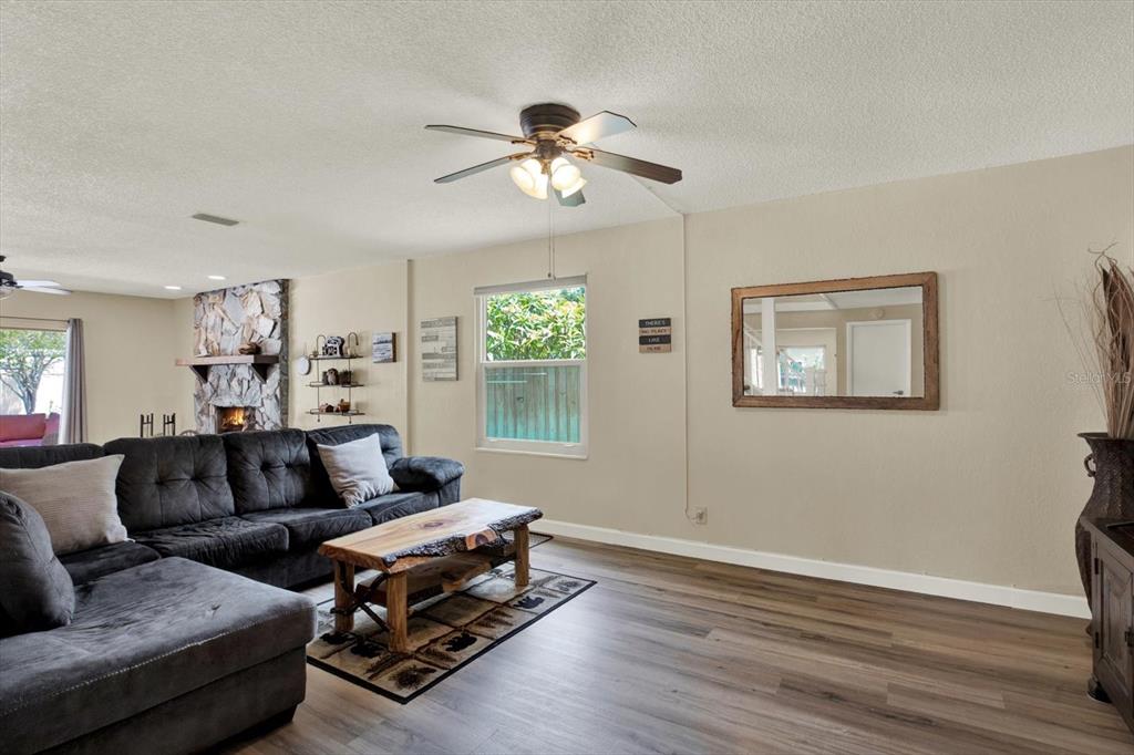 A living room features a dark sectional sofa, a wood coffee table, and a stone fireplace — 7363 ROSETREE PLACE E, SEMINOLE, FL