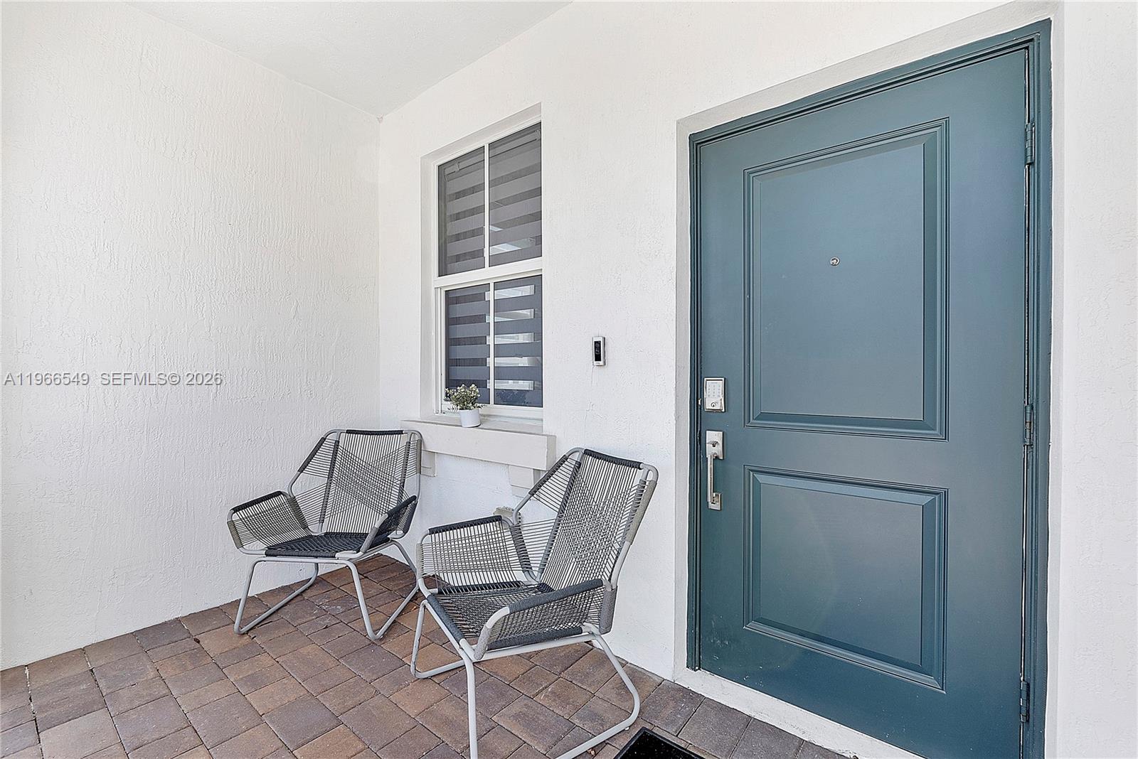 A patio features two chairs, a window with blinds, and a dark green front door — 2361 NW 125th St, Miami FL 33167, MIAMI, FL