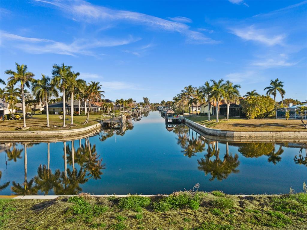 A canal view showing palm trees, grassy lawns, and houses along the water's edge — 2623 SW 35TH LANE, CAPE CORAL, FL
