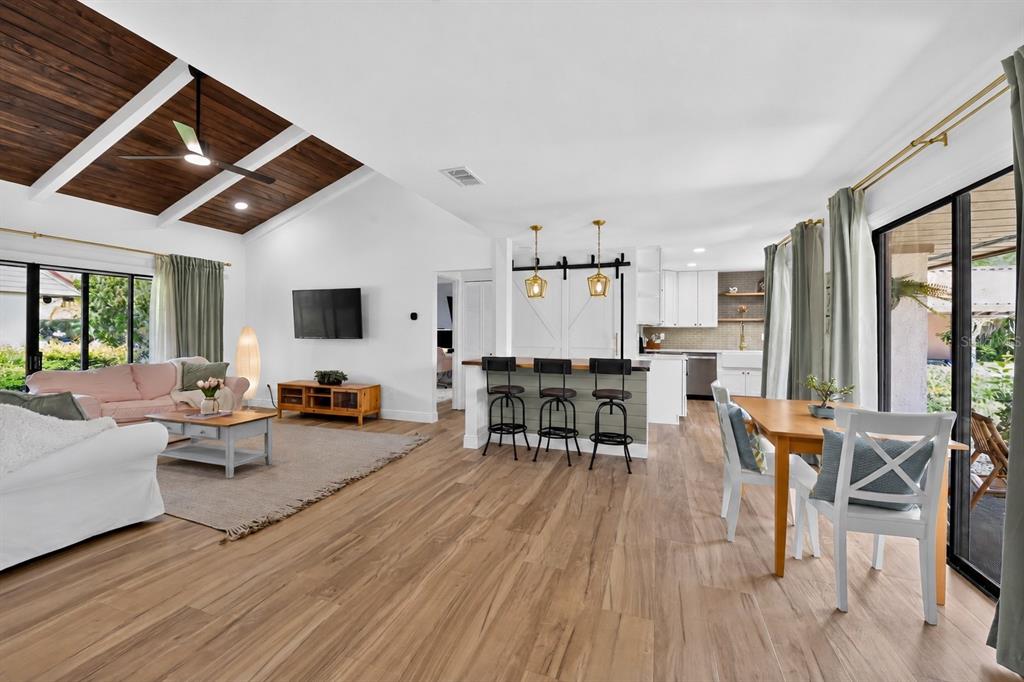 An open-concept living and dining area features vaulted wood-paneled ceilings and light wood flooring — 6378 DRAW LANE UNIT 36, SARASOTA, FL
