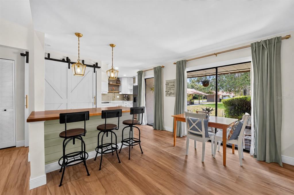 A kitchen with a breakfast bar, bar stools, and a dining area with sliding glass doors — 6378 DRAW LANE UNIT 36, SARASOTA, FL