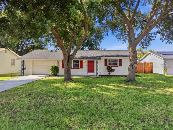A single-story white house with a red front door and a dark shingled roof — 5935 63RD AVENUE N, PINELLAS PARK, FL
