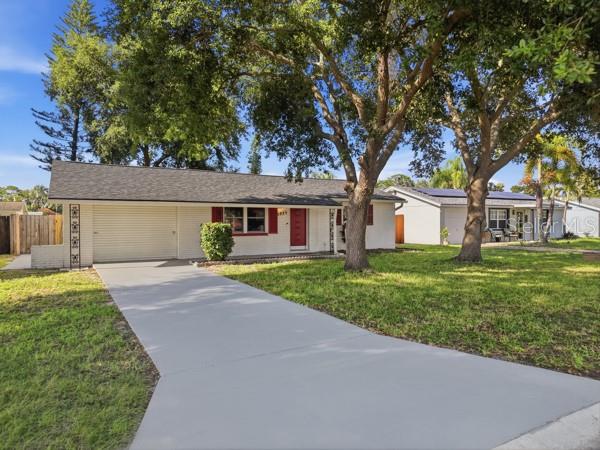 A single-story house with a white brick exterior, a red front door, and a concrete driveway — 5935 63RD AVENUE N, PINELLAS PARK, FL