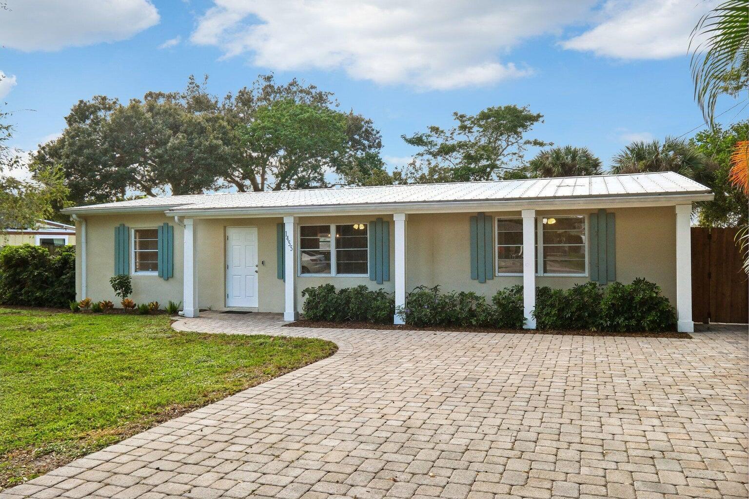 A single-story house with a metal roof, light-colored stucco, and a paved driveway — 1455 15th Avenue, Vero Beach FL 32960, VERO BEACH, FL