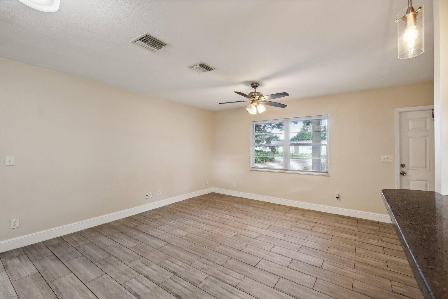 An empty room with light-colored walls, wood-look tile flooring, a ceiling fan, and a window — 1455 15th Avenue, Vero Beach FL 32960, VERO BEACH, FL