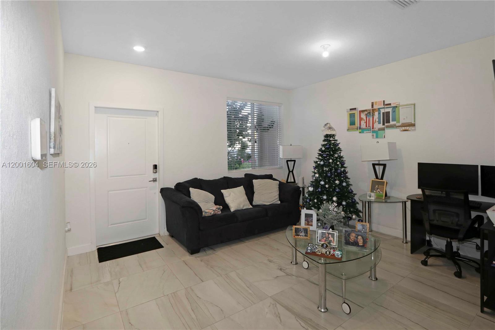 A living room features a dark sofa, a Christmas tree, and a glass coffee table — 2432 SE 10th Ct, Homestead FL 33035, HOMESTEAD, FL