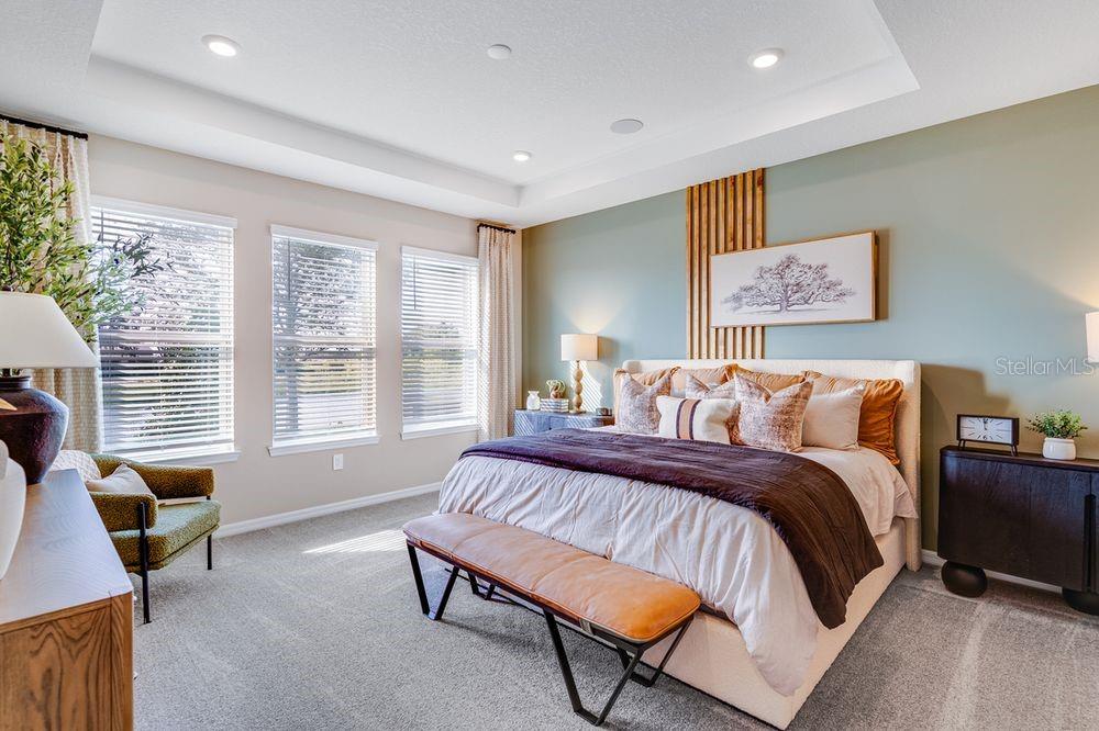 A bedroom features a king bed, a bench, a green accent wall, and three windows — 897 LADYFISH TRAIL, ST CLOUD, FL
