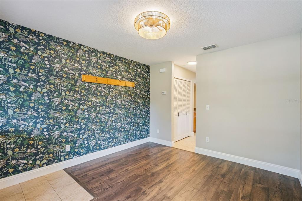 A room features dark floral wallpaper, a wooden coat rack, and wood-look flooring — 1459 AZALEA AVENUE, CASSELBERRY, FL