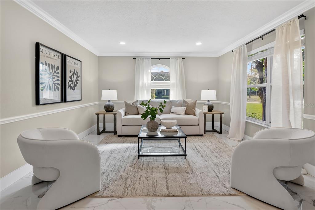 A bright living room features a white sofa, two modern armchairs, and framed wall art — 109 E 12TH AVENUE, WINDERMERE, FL