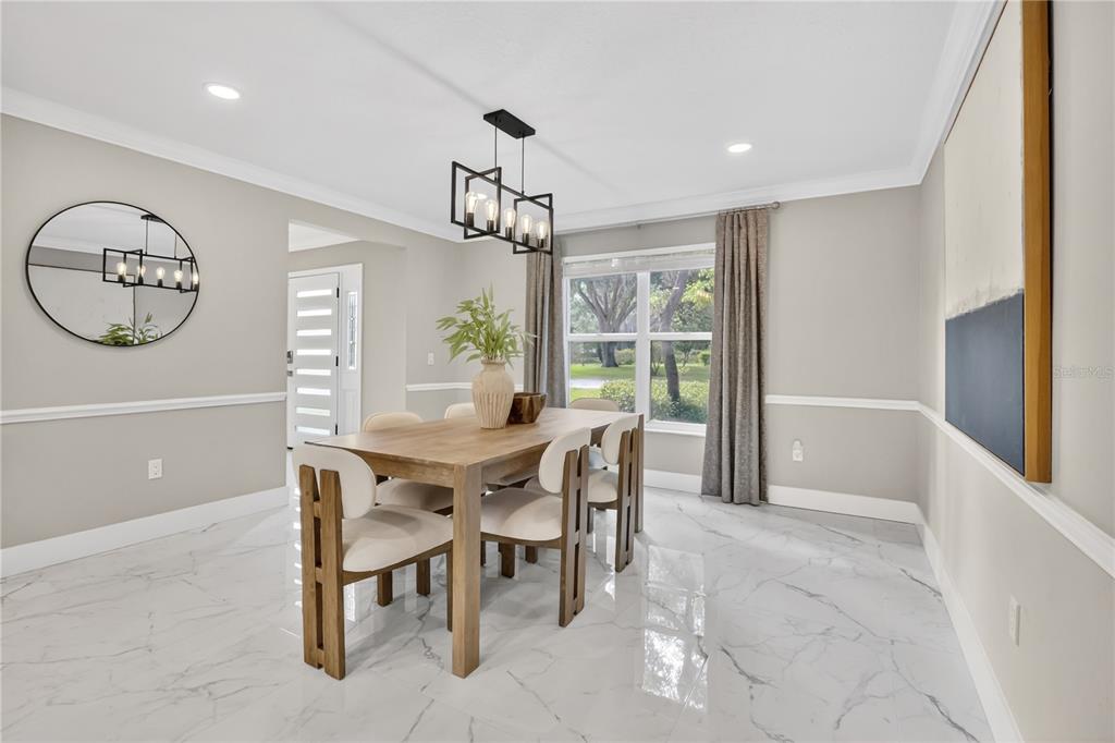 A dining room features a wooden table, upholstered chairs, a chandelier, and marble-look tile flooring — 109 E 12TH AVENUE, WINDERMERE, FL