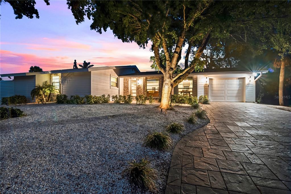 A single-story house with a stone-paved driveway and a large tree at dusk — 783 BIRDSONG LANE, SARASOTA, FL