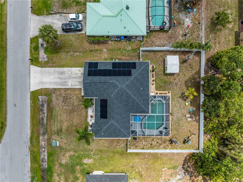 An aerial view shows a house with solar panels, a screened pool, and a driveway — 1729 MILAN STREET, NORTH PORT, FL