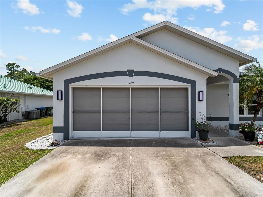 The exterior of a house features a concrete driveway and a garage with a screen — 1729 MILAN STREET, NORTH PORT, FL