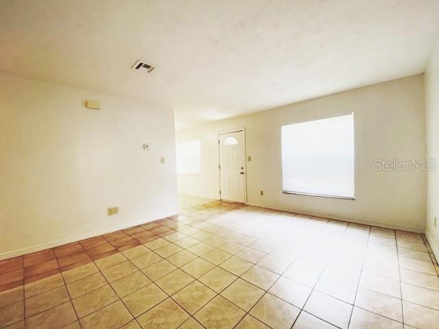 An empty room features light-colored tile flooring, white walls, and a white front door — 101 S FLAMINGO AVENUE, WINTER SPRINGS, FL