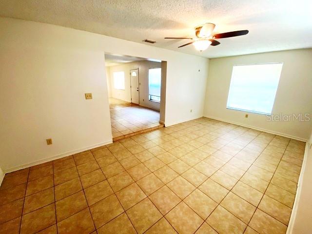 A room with light-colored walls, tiled flooring, a ceiling fan, and a large window — 101 S FLAMINGO AVENUE, WINTER SPRINGS, FL
