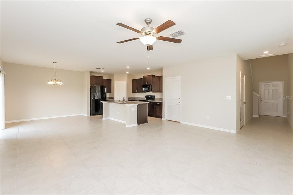 An open-concept kitchen with dark cabinets and a center island overlooks a spacious living area — 15519 WICKED STRONG STREET, SUN CITY CENTER, FL