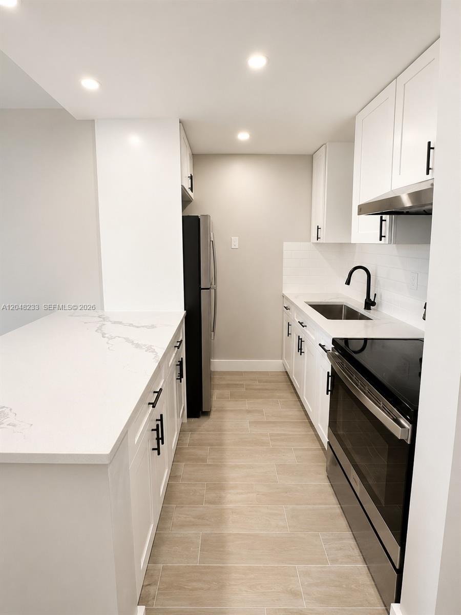 A modern kitchen features white cabinets, quartz countertops, stainless steel appliances, and wood-look tile flooring — 1530 SW 2nd St # 307, Miami FL 33135, MIAMI, FL