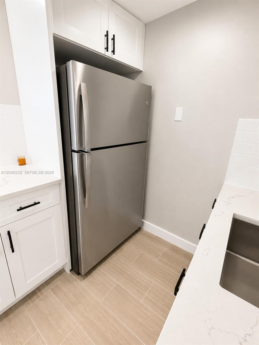 A stainless steel refrigerator is positioned between white cabinets and a light-colored countertop — 1530 SW 2nd St # 307, Miami FL 33135, MIAMI, FL