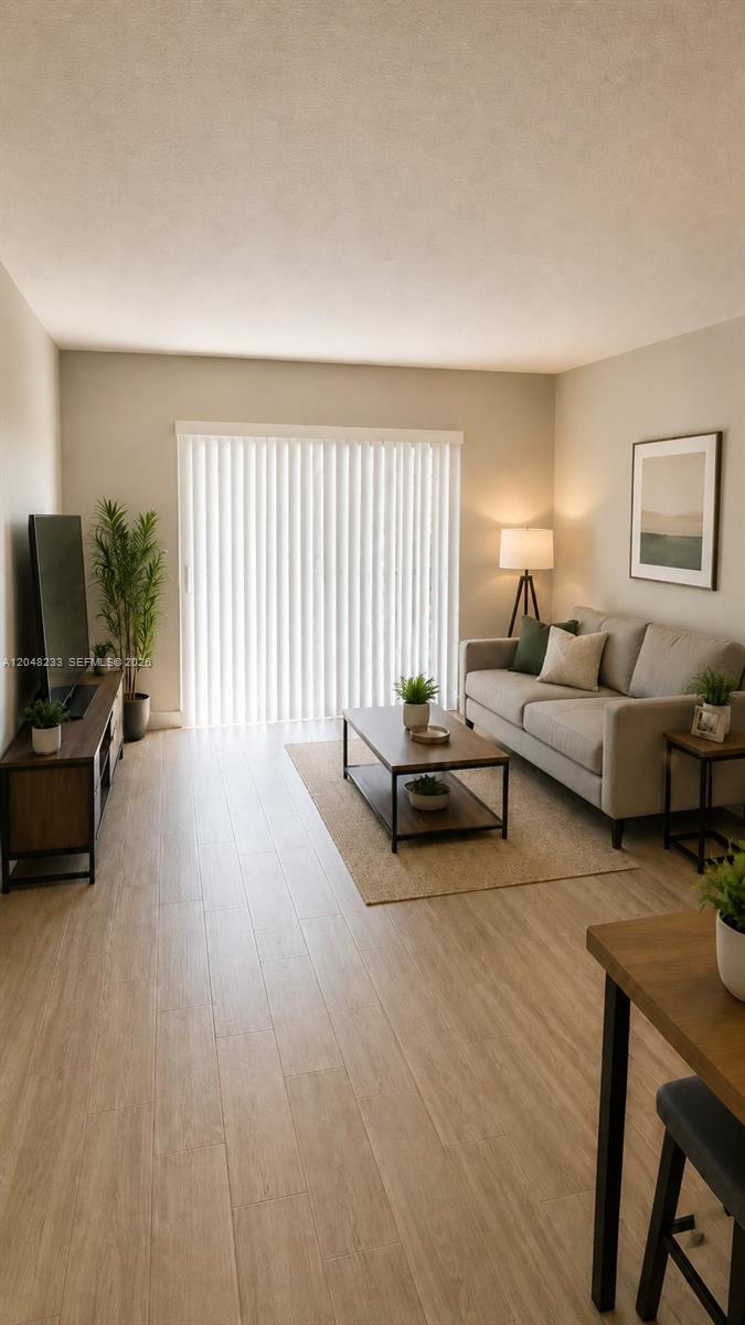 A living room features light wood-look flooring, a gray sofa, and a sliding glass door — 1530 SW 2nd St # 307, Miami FL 33135, MIAMI, FL