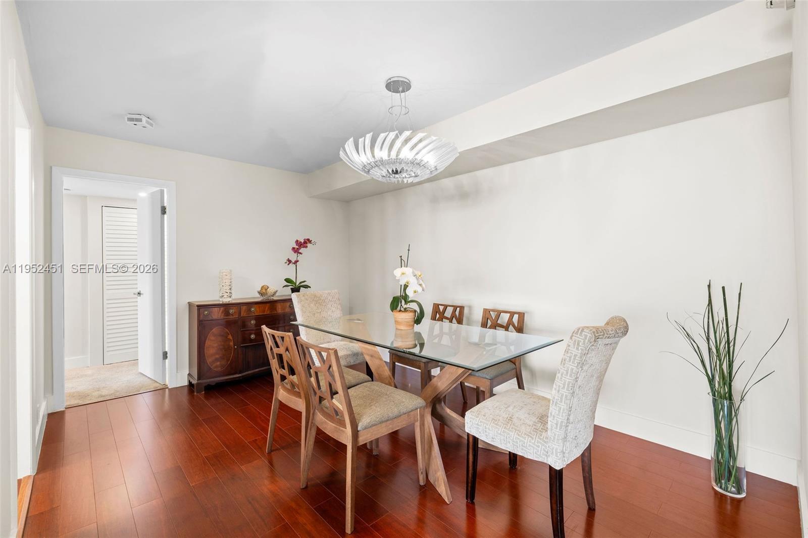 A dining room features a glass-topped table, upholstered chairs, a wooden sideboard, and hardwood floors — 4000 Towerside Ter # 2005, Miami FL 33138, MIAMI, FL