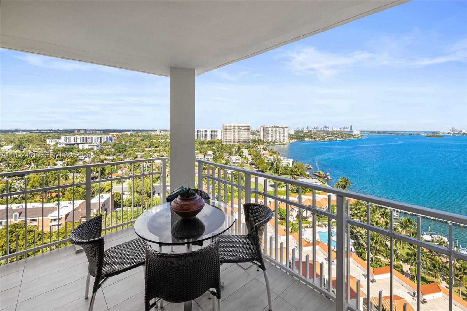 A balcony with a glass-topped table and chairs overlooks a bay and city skyline — 4000 Towerside Ter # 2005, Miami FL 33138, MIAMI, FL