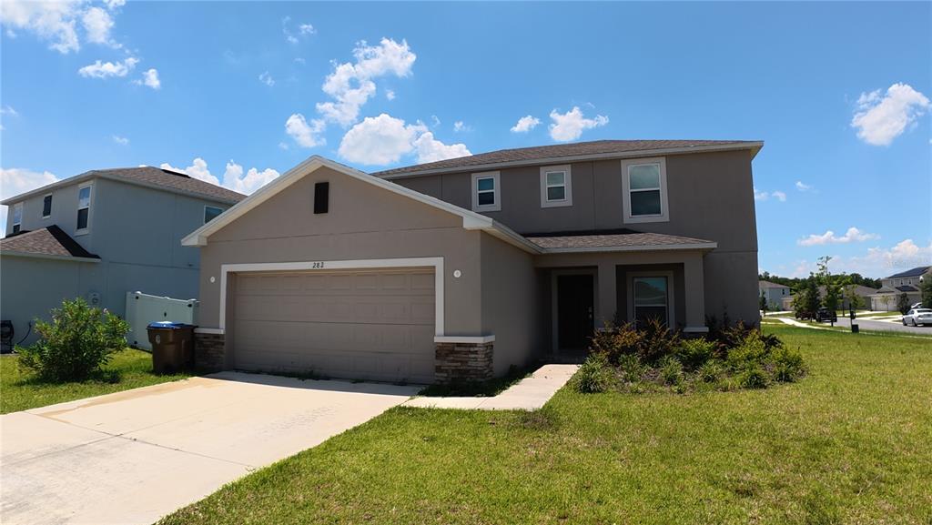 A two-story suburban house with a tan stucco exterior and a two-car garage — 282 AMBER WAY, KISSIMMEE, FL