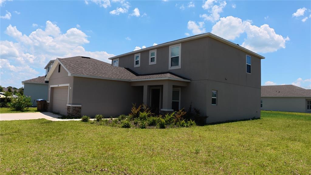 A two-story, tan-colored house with a garage and a covered front porch — 282 AMBER WAY, KISSIMMEE, FL