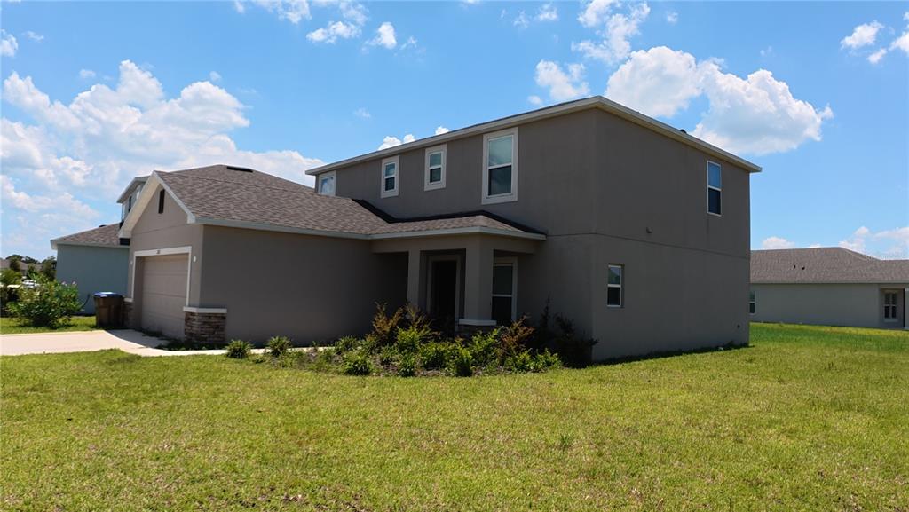 A two-story suburban house with a tan stucco exterior, a garage, and a front lawn — 282 AMBER WAY, KISSIMMEE, FL