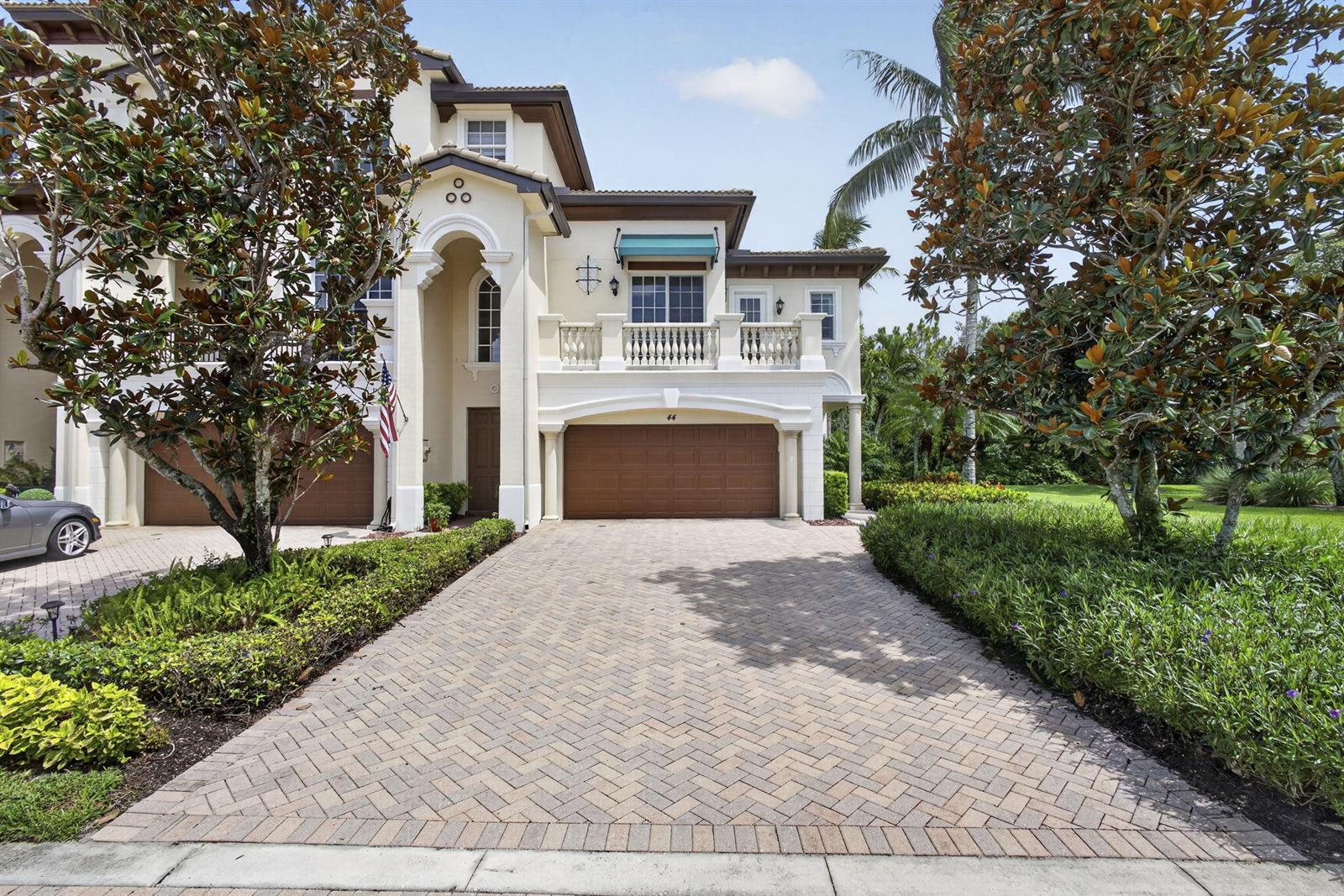 A two-story house with a paved driveway, a brown garage door, and a second-floor balcony — 222 Tresana Boulevard # 44, Jupiter FL 33478, JUPITER, FL