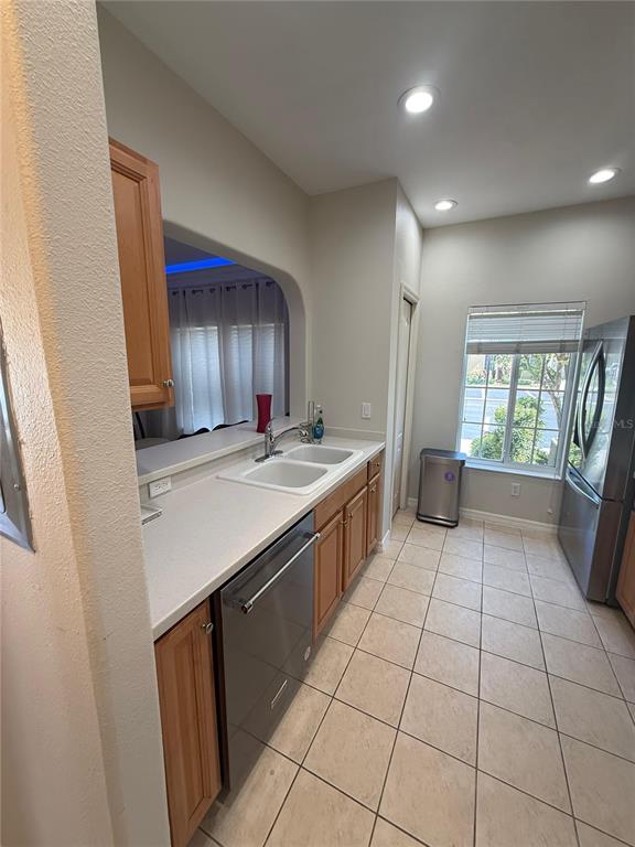 A kitchen features light-colored countertops, wood cabinets, stainless steel appliances, and tile flooring — 12985 COYOTE LN LANE, VENICE, FL