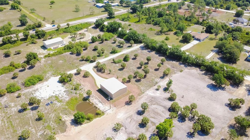 An aerial view shows a large metal building on a rural lot with scattered trees — 6041 GROVE BOULEVARD, PUNTA GORDA, FL