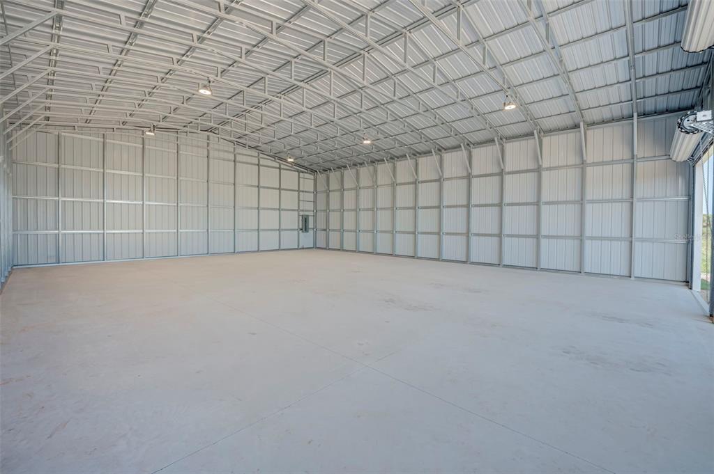 An empty, large metal warehouse interior features a concrete floor and exposed steel ceiling trusses — 6041 GROVE BOULEVARD, PUNTA GORDA, FL