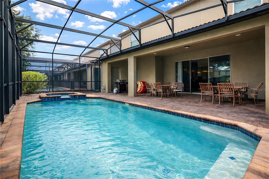 A screened-in patio features a swimming pool, a hot tub, and outdoor dining furniture — 2147 TRIPOLI COURT, KISSIMMEE, FL