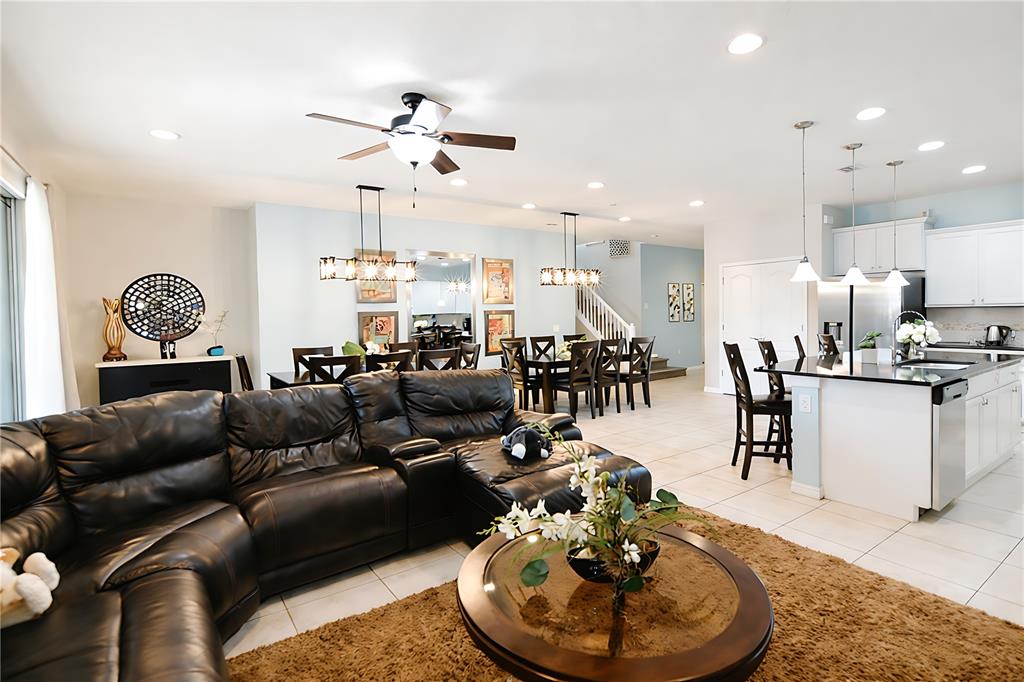 An open-concept living room and kitchen feature a leather sectional, dining area, and tile flooring — 2147 TRIPOLI COURT, KISSIMMEE, FL