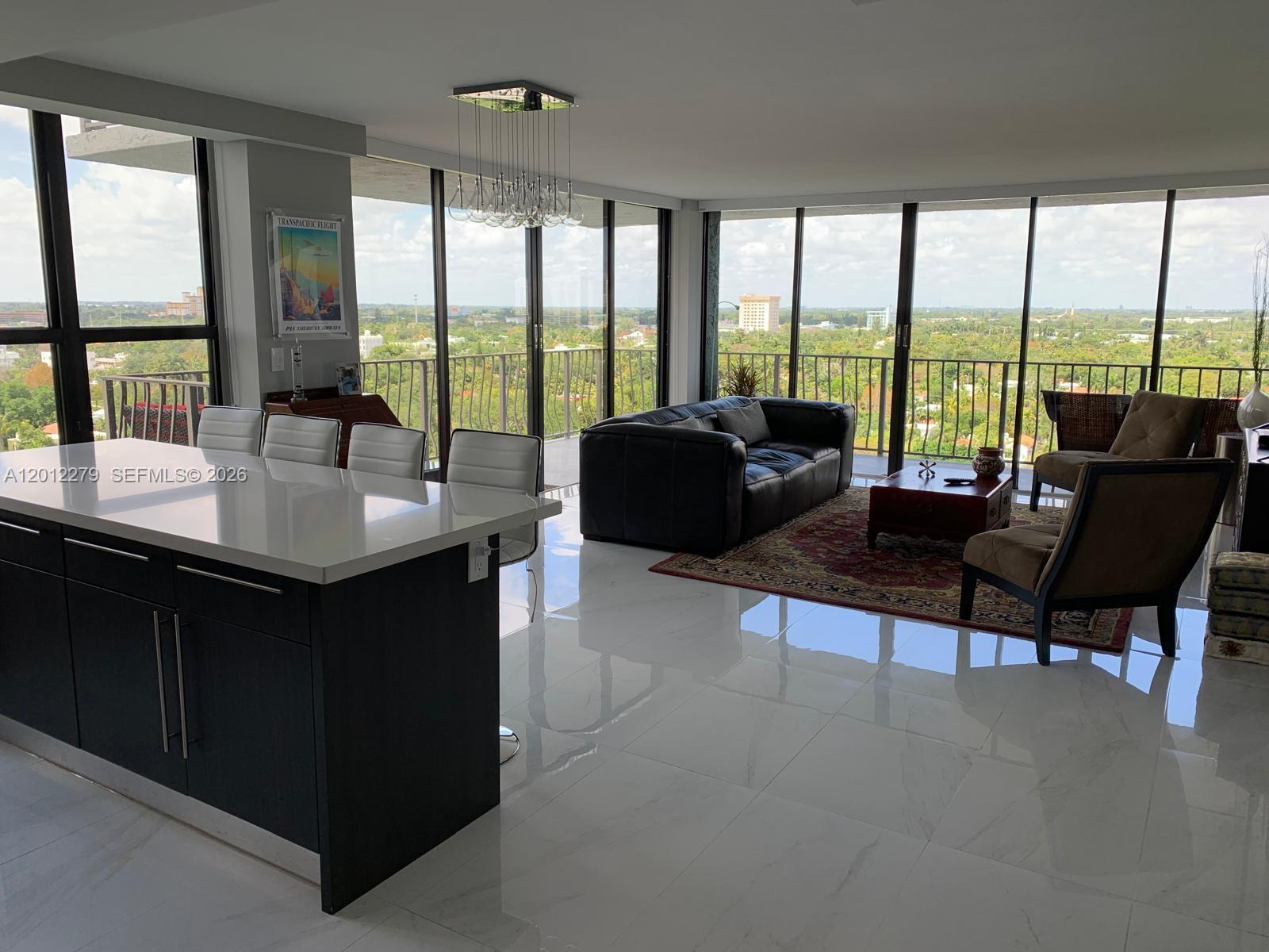 A modern open-concept living area features a kitchen island, white tile floors, and floor-to-ceiling windows — 780 NE 69th St # 1210, Miami FL 33138, MIAMI, FL