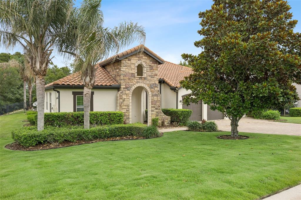 A single-story house with a stone facade, tile roof, and a manicured lawn — 16704 CARAVAGGIO LOOP, MONTVERDE, FL