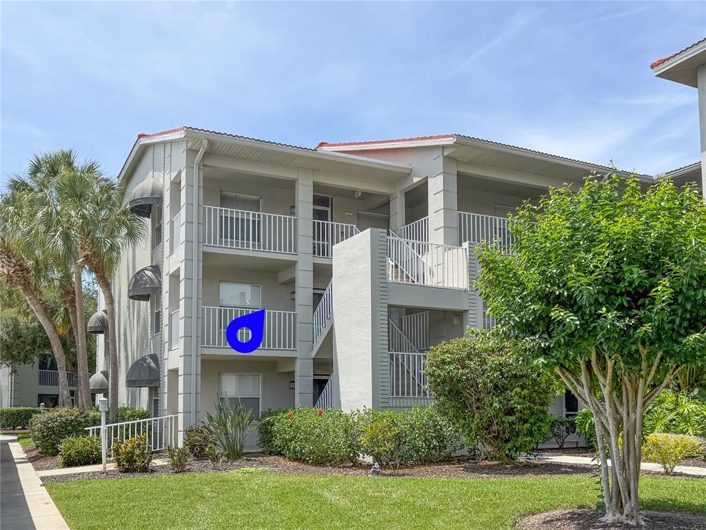 A three-story apartment building features white stucco walls, a red roof, and private balconies — 9320 CLUBSIDE CIRCLE UNIT 2201, SARASOTA, FL